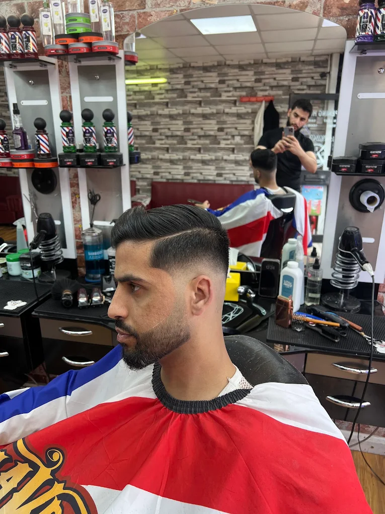 A barber at Reb Barber finishing a sharp fade inside the New Cross shop